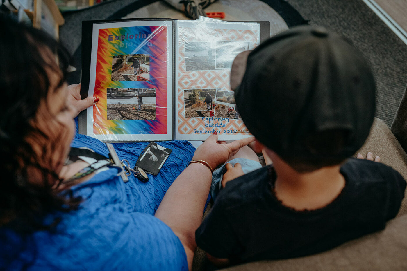 Over shoulder shot of a woman helping a child read a book.